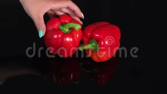 两个成熟多汁的红辣椒在黑镜背景上慢动作视频的预览图