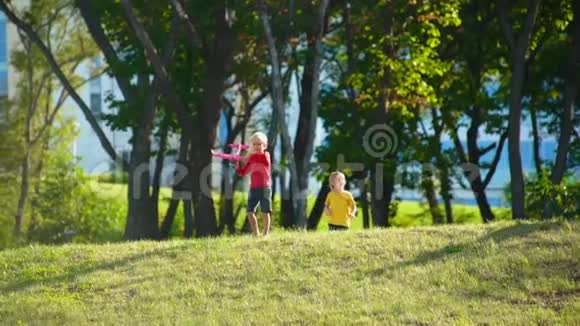 两个小男孩在草坪上玩飞机的慢镜头视频的预览图