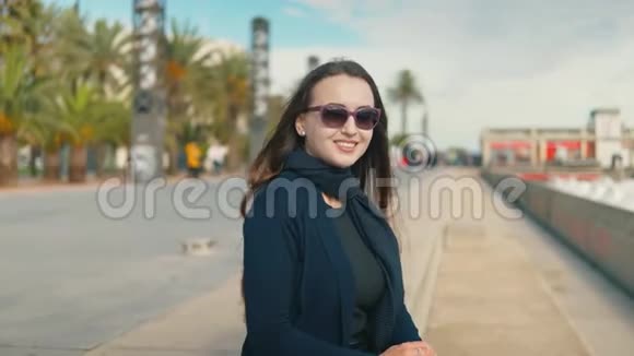 年轻的女游客坐在棕榈滩附近微笑着视频的预览图