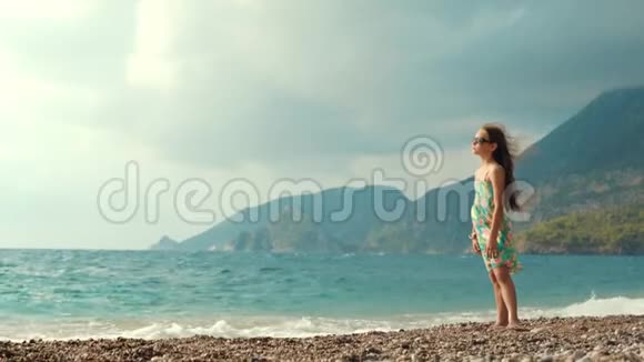 小女孩在海边掉头可爱的女孩在海滩上看海视频的预览图