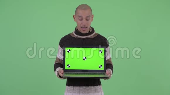 快乐的秃头多民族男人展示笔记本电脑看上去很惊讶视频的预览图