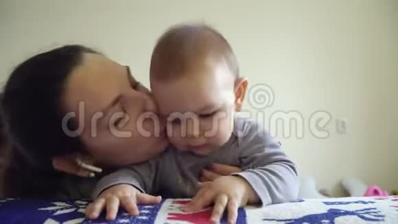 妈妈和宝宝接吻快乐拥抱妈妈妈妈带着无线耳机视频的预览图