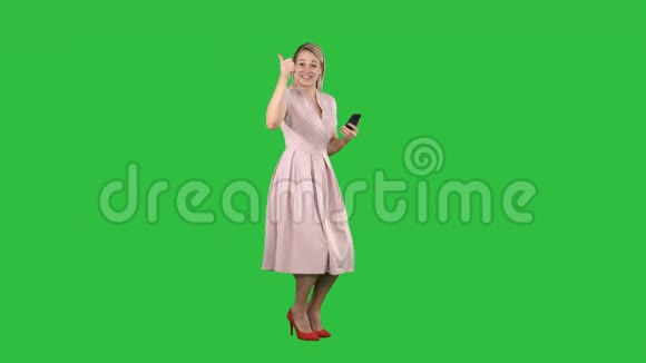 笑着美丽的年轻女子穿着粉红色的裙子站在绿色的屏幕上Chroma键视频的预览图