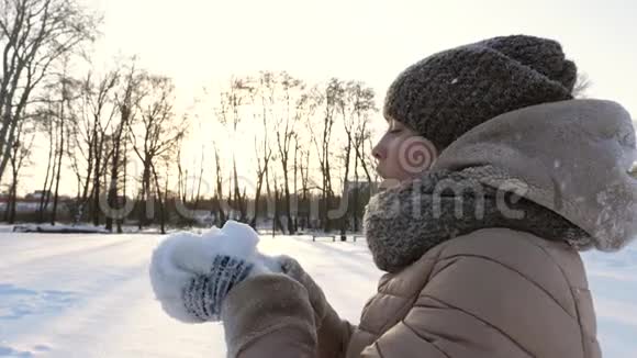 美丽的女孩吹在白色的冷雪上冬天的时候冰雪游戏视频的预览图