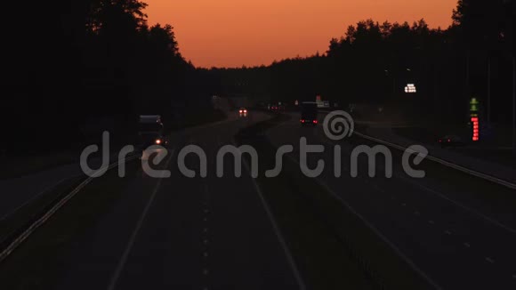 在日落的背景下高速公路上交通车辆的夜间移动橙色天空物流概念背景视频的预览图