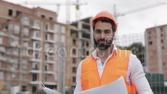 施工工人戴橙色头盔看镜头的肖像有建筑工程的建筑工人站起来视频的预览图
