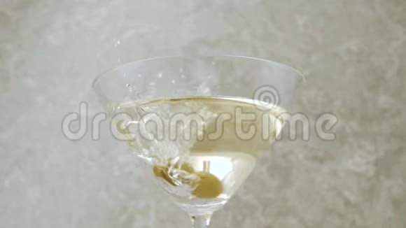 豪华马提尼两颗美味的绿橄榄用马提尼在浅色背景下倒入一个玻璃杯中佛蒙特州视频的预览图