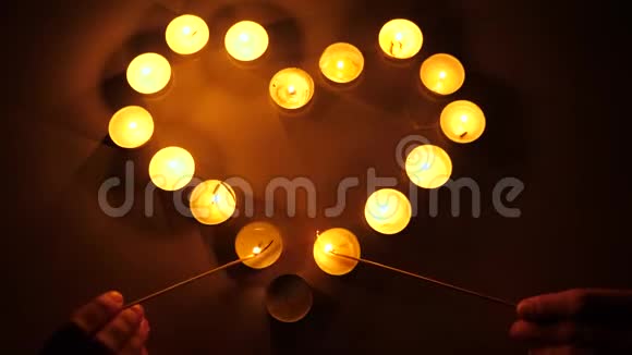 从蜡烛中闪烁的光蜡烛闪烁的背景茶点燃蜡烛形成心脏的形状爱的主题概念视频的预览图