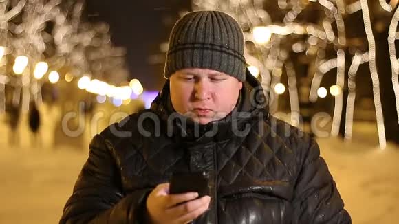 冬夜使用手机的年轻胖子户外画像视频的预览图