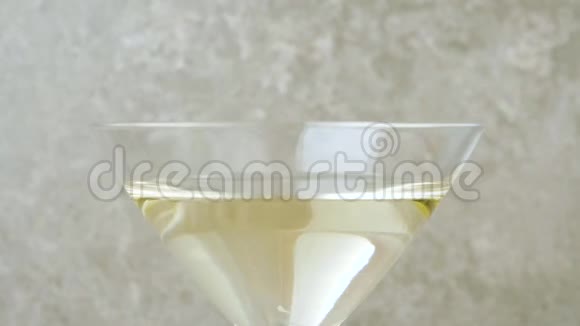 豪华马提尼两颗美味的绿橄榄放在玻璃杯里杯中的马提尼放在浅色背景下视频的预览图