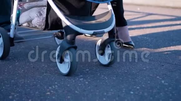 骑在柏油路上的婴儿车的的特写一对相爱的夫妇和一个孩子在街上散步视频的预览图