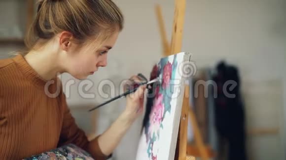 勤奋的美术学生漂亮的女孩正在画漂亮的画花在教室里站在画架附近人就是视频的预览图
