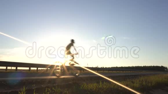 一个孩子和他的父亲骑着自行车在道路上的背景下日落旅行和度假的概念复制视频的预览图