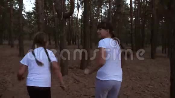 十几岁的女孩在松林里跑来跑去笑孩子们在公园里和爸爸玩视频的预览图