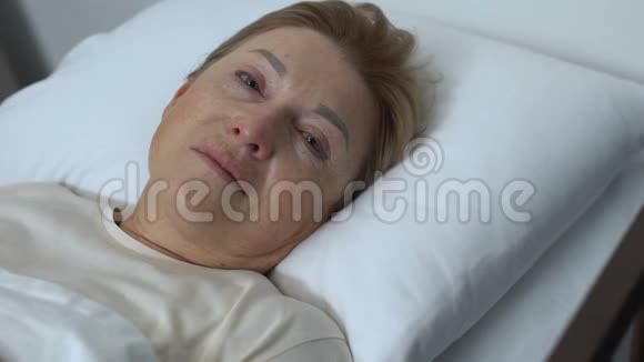 虚弱的哭泣的女士躺在床上看着摄像机临终关怀中心绝望视频的预览图
