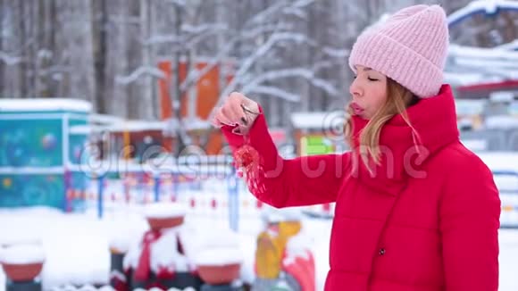 肖像可爱的年轻女子穿着红色的冬衣手里拿着一束玫瑰吹着雪视频的预览图