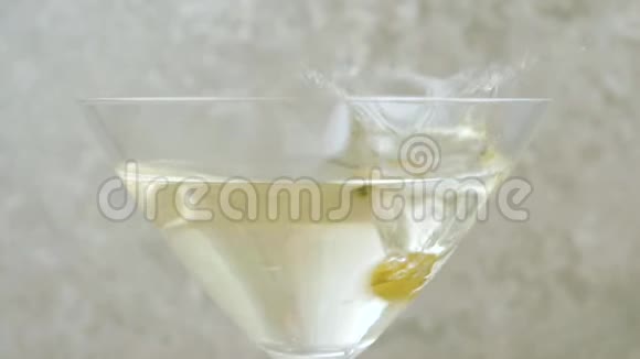 豪华马提尼美味的绿橄榄用马提尼在浅色背景下倒入玻璃杯中佛蒙特州视频的预览图