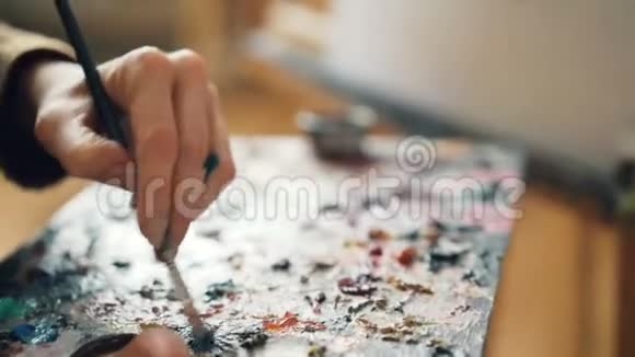 特写女性手拿调色板和画笔混合颜色然后在画布上画花艺术作品视频的预览图