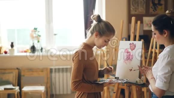 年轻的女性美术老师和学生在绘画学校上课女孩在调色板上混合颜色而大师视频的预览图