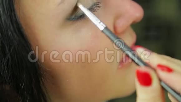一个年轻的黑发女人用刷子涂上眼影概况视频的预览图
