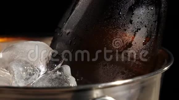 新鲜啤酒一个带有美味工艺啤酒的棕色瓶子在黑色背景下旋转桶上有冷的真冰视频的预览图