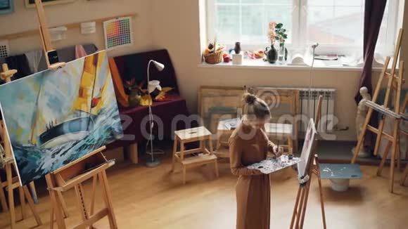 有创造力的人是在艺术工作室用油画颜料在调色板和画笔上作画女孩专注于工作视频的预览图