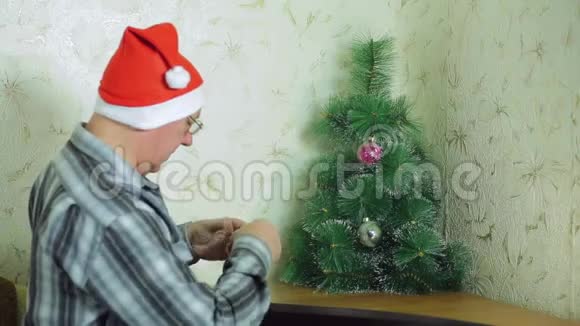 一个戴着圣诞老人帽子的人正在整理节日舞会来装饰圣诞树视频的预览图
