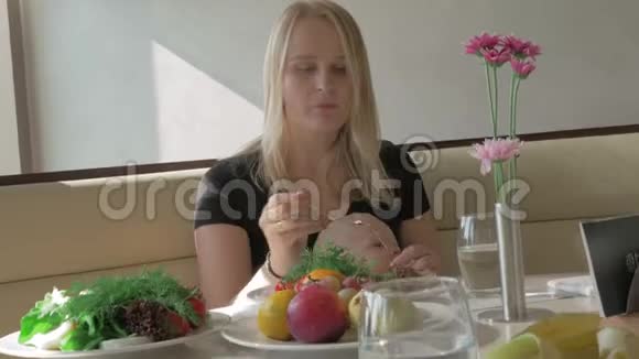 一个抱着孩子的女人正在吃饭视频的预览图