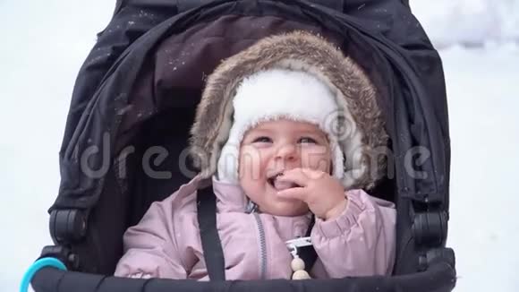 小女孩微笑着坐在雪橇婴儿车上冬雪日冬装4k视频的预览图