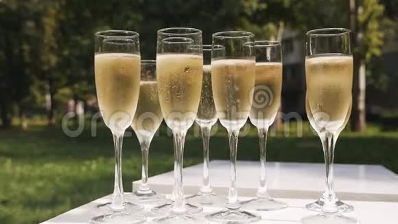 带有气泡的香槟酒杯站在自然背景的白色桌子上视频的预览图