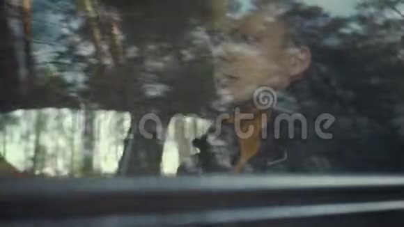 人骑着一辆车在乡间小路上车窗上的树木视频的预览图