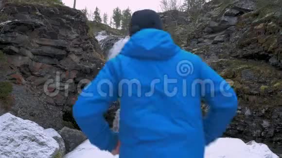 一个男子旅行者站在一个美丽的山瀑布附近享受着美丽的风景放松的好地方视频的预览图