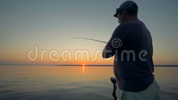 日出时钓鱼过程中的成年雄性渔民视频的预览图