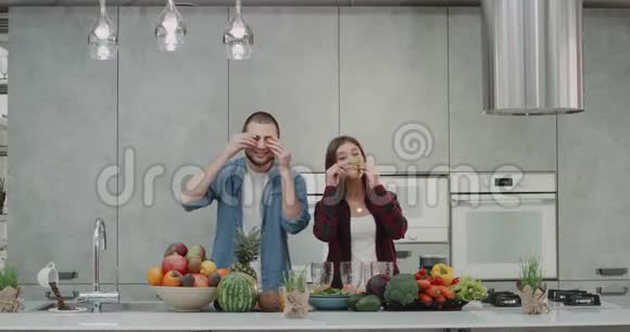 在现代化的厨房里一对年轻夫妇在做胡子之前一起用蔬菜做胡子视频的预览图