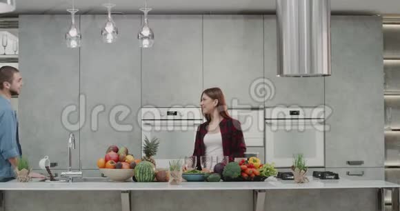 男人和女人在早上互相亲吻在现代厨房做早餐男人喝酒视频的预览图