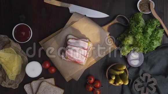 用培根和沙拉片做三明治时厨师在木板上的三明治里加入沙拉然后做视频的预览图