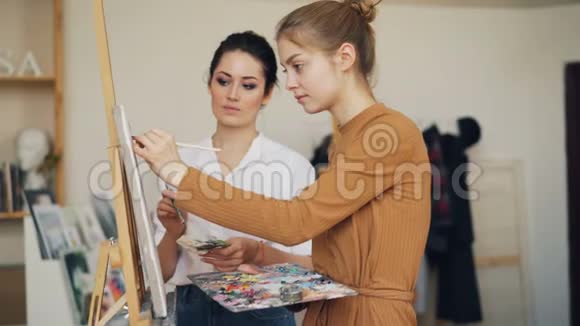 迷人的艺术学生女孩在有经验的女老师的指导下在工作室画画师父在说话视频的预览图