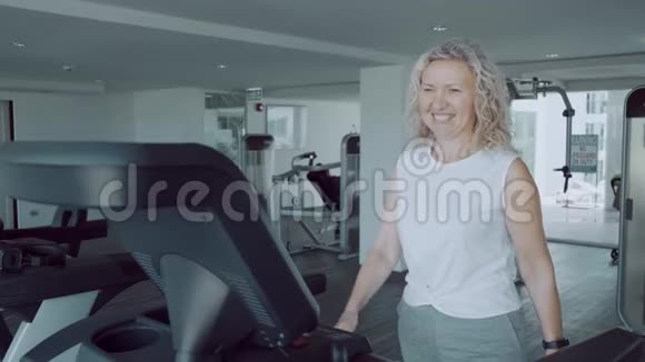 一位老年妇女正在健身房的跑步机上做运动有氧运动钟视频的预览图