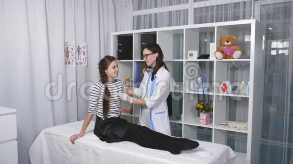 女医生助理在听诊器病人少女的帮助下检查和敲击视频的预览图