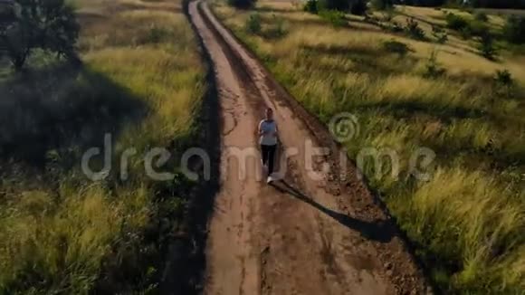 空中射击妇女在农村公路上奔跑视频的预览图