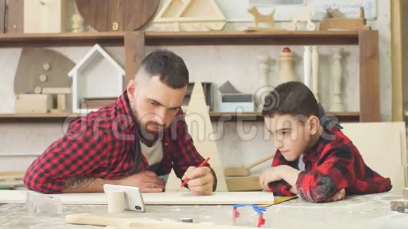 爸爸和儿子一起看智能手机同时选择一个家庭杰作的模型视频的预览图
