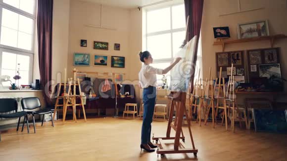 创意女孩专注于用油画颜料在调色板上画海洋景观用画笔站在前面视频的预览图
