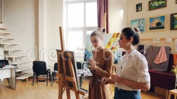 有经验的艺术家正在教可爱的女学生画花解释她的绘画技巧和分享视频的预览图