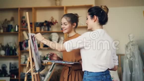 年轻的女美术老师和学生在创意工作室一起画画上课时说话微笑好吧视频的预览图