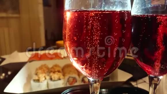 在带有红香槟酒的玻璃中在带有寿司的桌子上在背景上滚动视频的预览图