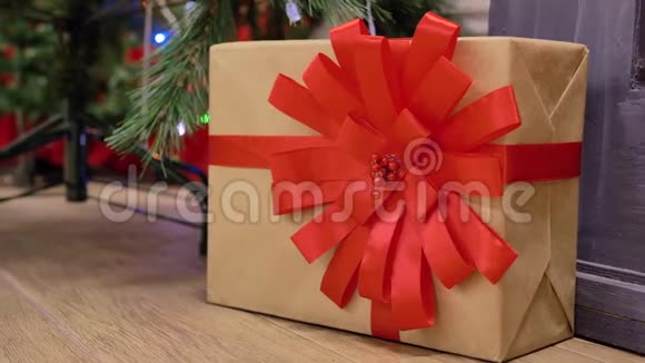 盒子放在牛皮纸上用红丝带系着用蝴蝶结系在圣诞树旁边视频的预览图