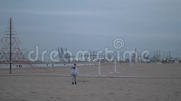 寒冷的一天小男孩在海滩上散步视频的预览图