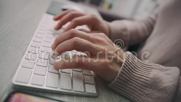 女性手在电脑键盘上打字女人用手机发短信视频的预览图