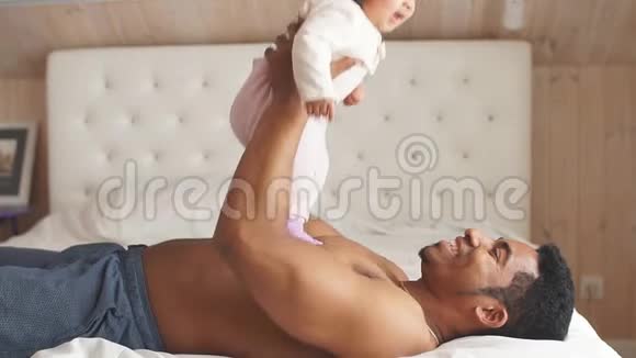 嬉戏的父亲扶着小女儿躺在床上视频的预览图