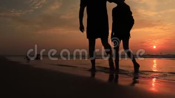 日落时分父子俩在海滩上散步友好家庭的概念视频的预览图